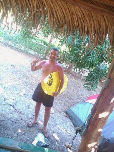 a man holding a yellow surfboard with a smile at Mal Pais Surf Camp in Santa Teresa Beach