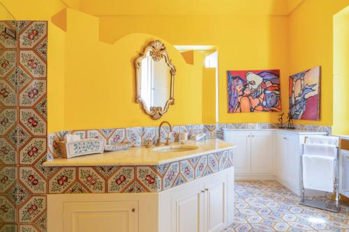 a yellow bathroom with a sink and a mirror at Capo Santa Fortunata in Sorrento