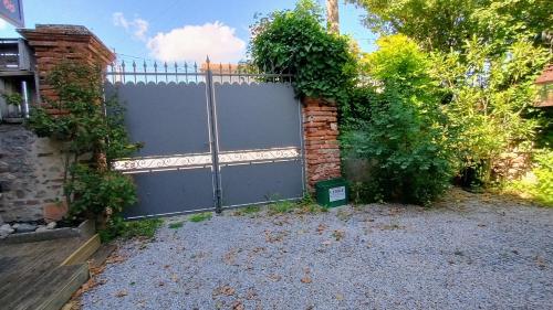 a fence in a yard next to a building at 16 Bis-Gîte-Hôtel-Appartement in Marssac-sur-Tarn