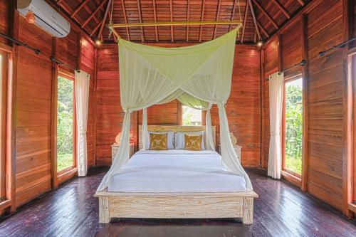 a bed with a canopy in a room with windows at Ubud Sawah Scenery Villa and Homestay in Tegalalang
