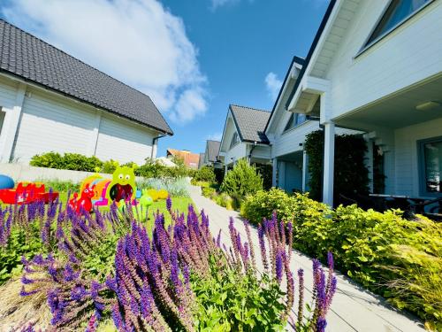 a garden with purple flowers in front of a house at Biale Domki Paula Rewal - Domki z klimatyzacja, w obiekcie Jacuzzi i darmowe Wifi! in Rewal