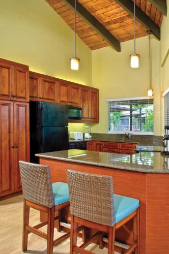 a kitchen with wooden cabinets and a black refrigerator at Club Wyndham Ka Eo Kai in Princeville