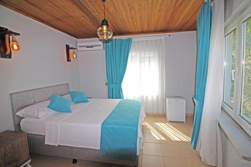 a bedroom with a bed and a window with blue curtains at Hambarlı Otel in Bozcaada