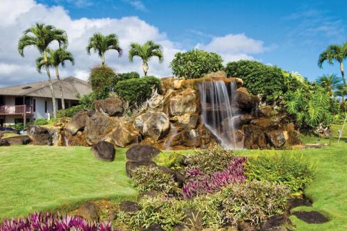a waterfall in a garden with flowers at Club Wyndham Ka Eo Kai in Princeville