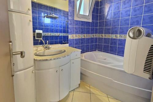 La salle de bains est pourvue de carrelage bleu, d'un lavabo et d'une baignoire. dans l'établissement Lej plage, à Valras-Plage