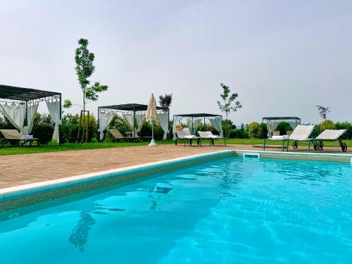a swimming pool with chairs and a gazebo at Giotto Country House & Spa in Assisi