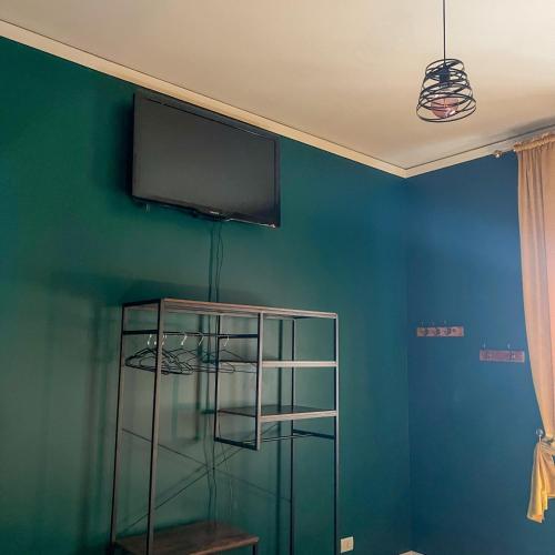 a room with a tv on a blue wall with a shelf at B&B La Fontana in Spilamberto