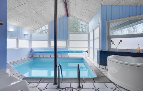 a bathroom with a large swimming pool with a tub and a sink at Nice Home In Glesborg With Sauna in Fjellerup Strand