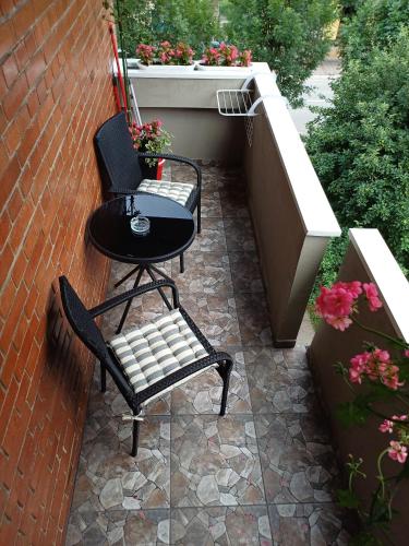 a patio with two chairs and a table and flowers at Eva apartman in Gornji Milanovac