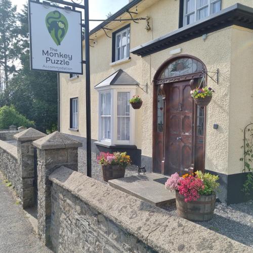 a building with a wooden door and flowers in pots at The Monkey Puzzle in Bunclody