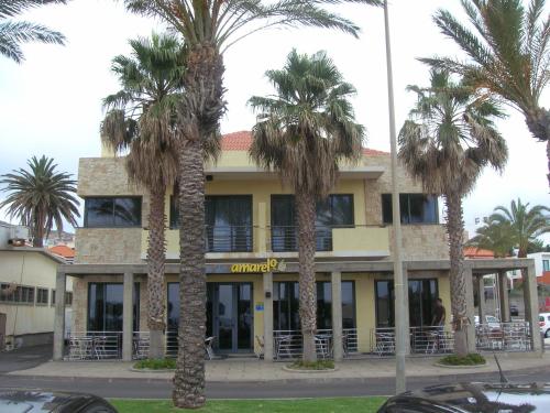 a building with palm trees in front of it at Apartamentos Amarelo in Caniçal