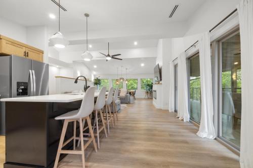 a kitchen with a bar with white counter chairs at Willow - 99 Ridge Lane in Branson