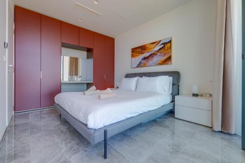 a bedroom with a large white bed with red walls at Mercury Tower Apartments in St Julian's