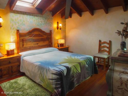 a bedroom with a bed and two tables and a chair at Hotel Rural Sucuevas in Mestas de Con