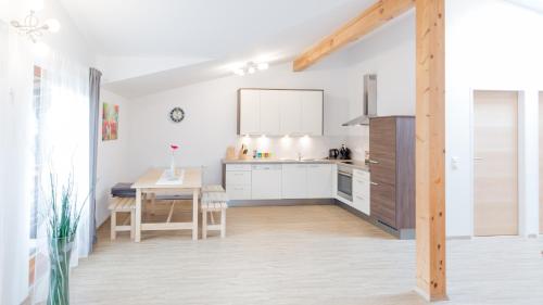 cocina con armarios blancos y mesa de madera en Merlin, en Lienz