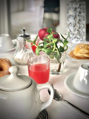a table with a tea pot and a glass of red drink at Hotel La Parigina in Lignano Sabbiadoro
