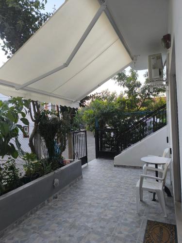 a white patio with a table and a white umbrella at Mary's house in Kyparíssion