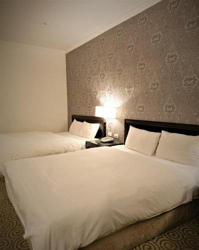 two beds in a hotel room with white sheets at Well Garden Hotel in Taoyuan