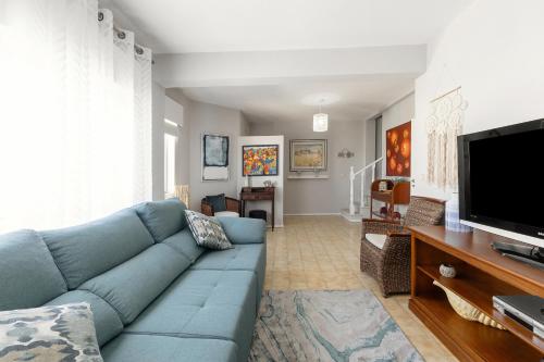 a living room with a blue couch and a flat screen tv at Consolação Beach Villa in Atouguia da Baleia