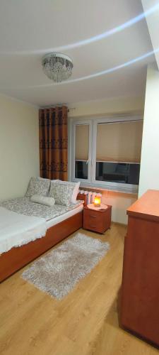 a bedroom with a bed and a table and two windows at Apartament Bella Zdrój in Głuchołazy