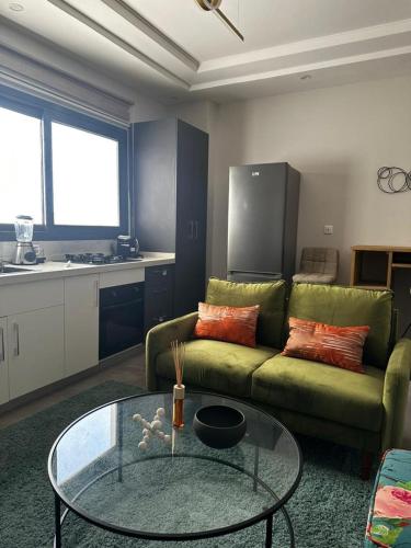 a living room with a green couch and a glass table at Studio meublé à Mermoz in Dakar