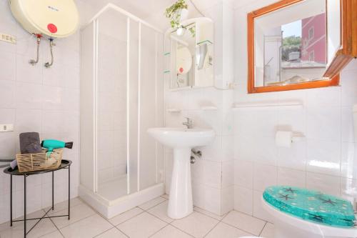 a white bathroom with a sink and a mirror at Naos Casa Vacanze in Iglesias