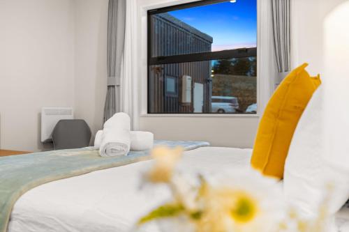 a bedroom with a bed with towels and a window at Starlet 11 in Lake Tekapo