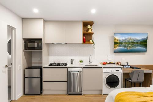 a kitchen with white cabinets and a washer and dryer at Starlet 11 in Lake Tekapo