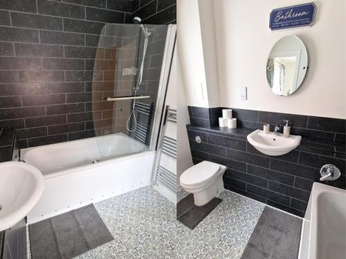 a bathroom with a tub and a toilet and a sink at Luxury City Centre Apartment- Free Parking in Leicester