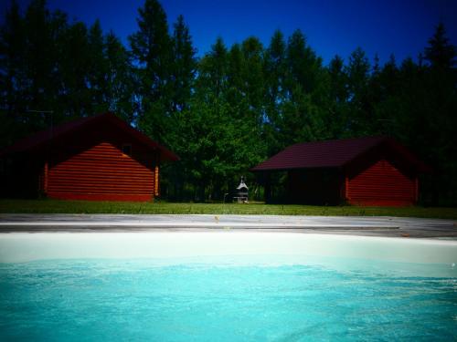 two red barns and a pool of water in front of two buildings at Ignaszówka in Radawa