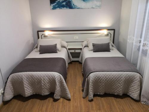two beds in a small room with white walls at Pensión Plaza in Quintáns