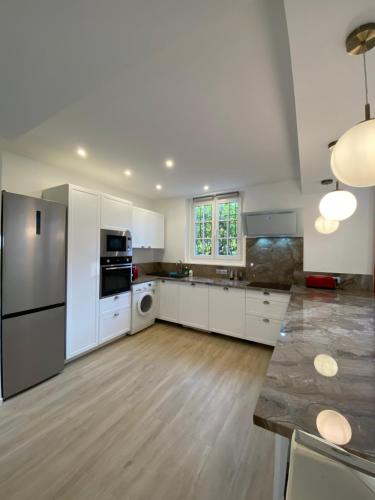 une grande cuisine avec des placards blancs et des appareils en acier inoxydable dans l'établissement 3P calme en RDJ - Quiet 2 BR with large terrace, à Cannes