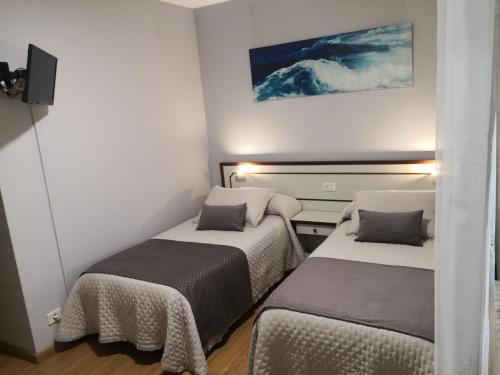 a small room with two beds and a tv at Pensión Plaza in Quintáns