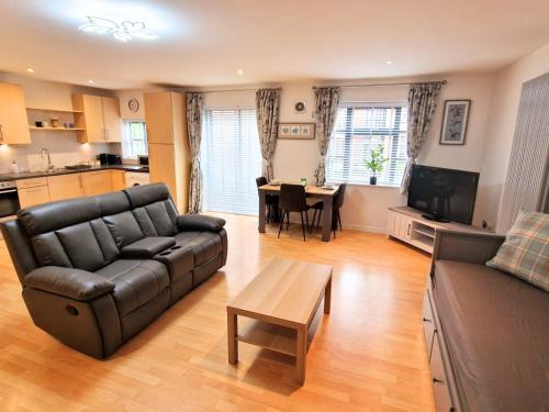 a living room with a black leather couch and a table at Luxury City Centre Apartment- Free Parking in Leicester