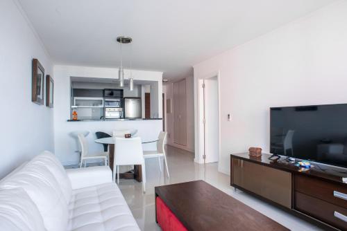 a living room with a white couch and a television at Departamento en Punta del Este in Punta del Este