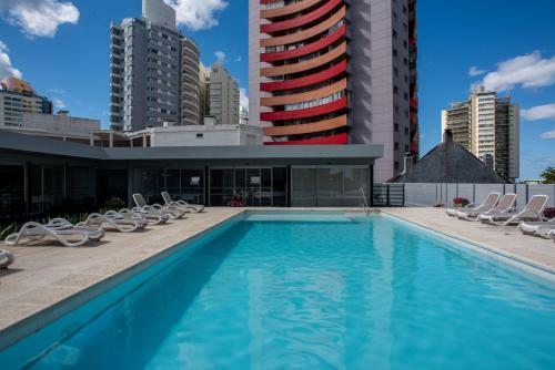a swimming pool with chairs and a building at Departamento en Punta del Este in Punta del Este