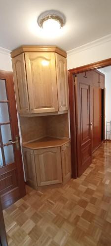 an empty kitchen with wooden cabinets in a room at EnVIVEIRO Destino Playa de Covas in Viveiro