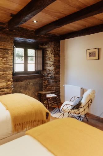a bedroom with a bed and a chair and a window at Casa do Corral in Hospital
