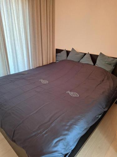 a bed with a purple comforter and pillows at zonnig vernieuwd penthouse dicht bij het strand in Knokke-Heist