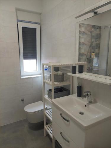a white bathroom with a toilet and a sink at Apartman Zlata in Pakoštane