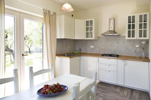 - une cuisine avec des placards blancs et un bol de fruits sur une table dans l'établissement L'OrtoBio, à Sarzana