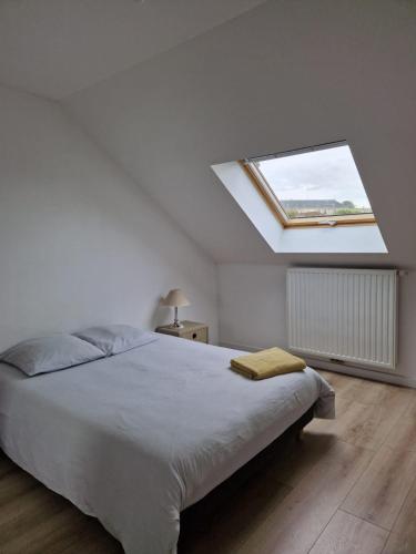 - une chambre blanche avec un grand lit et une lucarne dans l'établissement Maison neuve proche Versailles et Paris, à Morainvilliers
