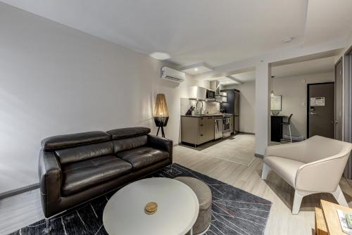 a living room with a leather couch and a table at 77 St-Vallier Apparts Hôtel in Quebec City