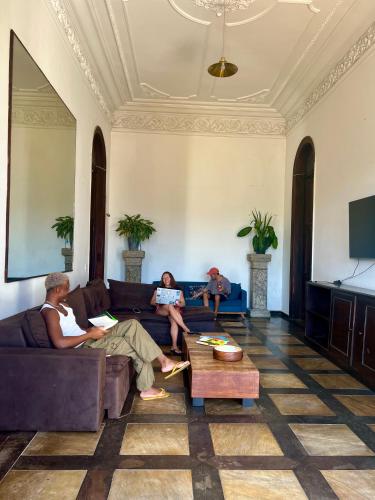 three people sitting on a couch in a living room at Castelo dos Tucanos Host in Rio de Janeiro