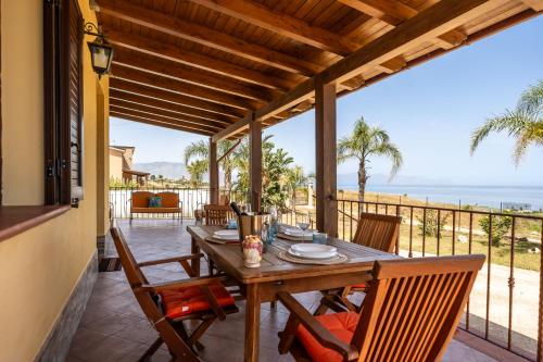 a wooden table and chairs on a patio with the ocean at Villa Panorama in Trappeto