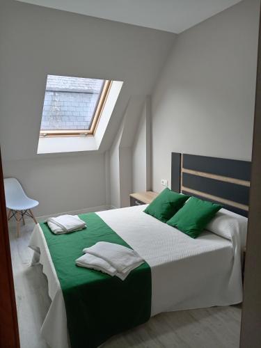 a bedroom with a bed with green sheets and a window at Apartamentos Mar y Playa in Moaña