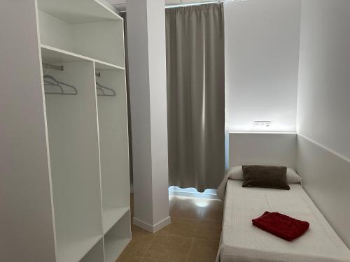 a small room with a bed and a window at Albergue O Pedrón Hostel & Rooms in Padrón