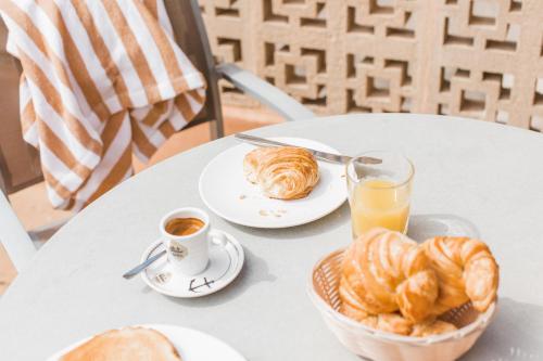 a table with a plate of croissants and a cup of orange juice at Hotel Golf Beach in Santa Ponsa