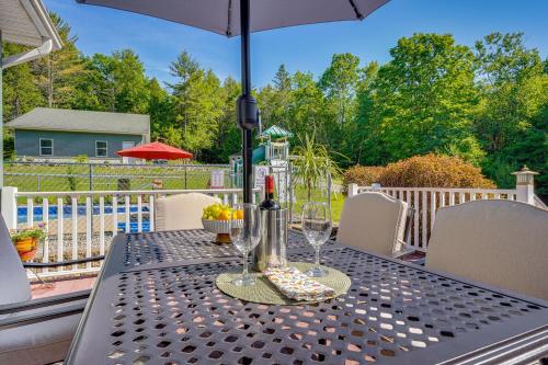 a table with wine glasses and an umbrella on a patio at Adirondack Retreat with Heated Pool and Scenic Views! in North Creek