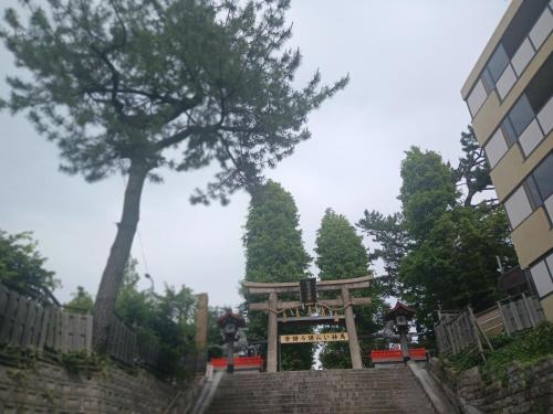 a wooden gate in a park with a tree at 鹿の宿 in Osaka